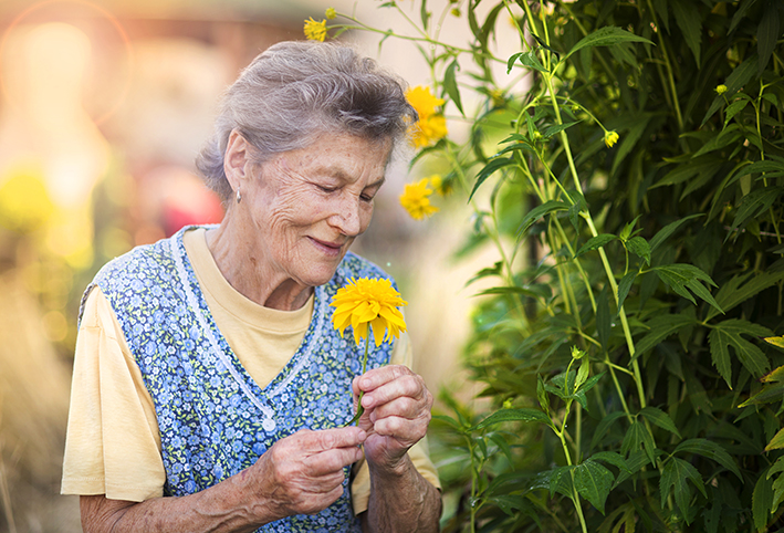 Ältere Dame mit gelber Blume