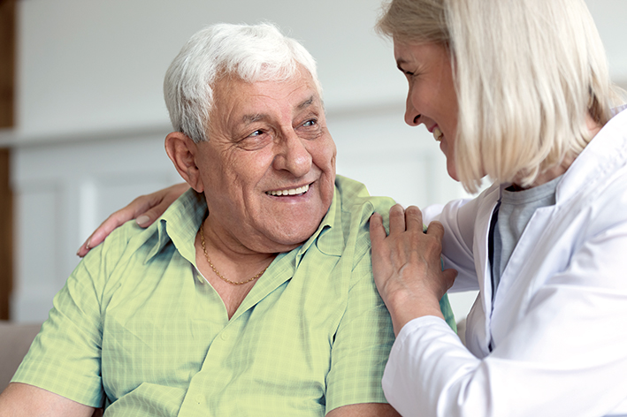 Krankenschwester unterhält sich mit älterem Herrn