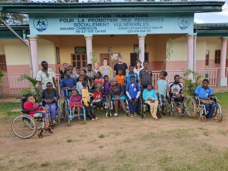 Gruppenbild von einem Projektbesuch. Es sind über 25 Menschen zu erkennen, wovon sieben im Rollstuhl sitzen.